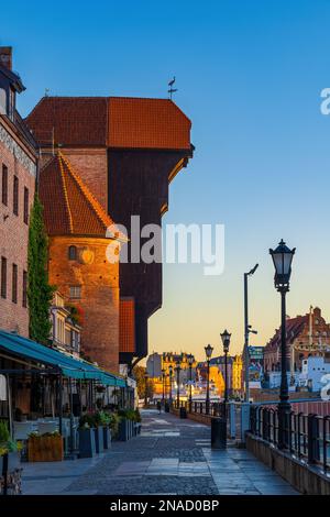 Medieval Crane at sunrise on Long Embankment riverside promenade in Old Town of Gdansk in Poland, symbol of the city. Stock Photo