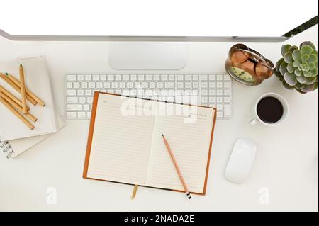Minimal white office desk workspace top view with empty pages notebook or diary, pencils, computer, vintage alarm clock and decor. Stock Photo