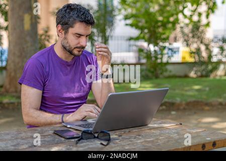 young bearded man with a tired look looking at his PC Stock Photo