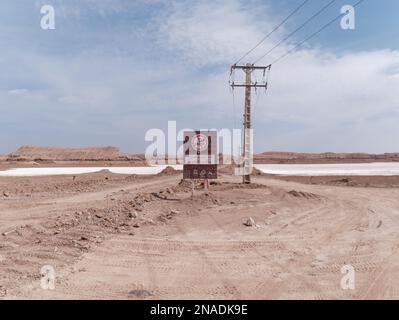 A desert landscape featuring an empty dirt road with a signpost in the foreground Stock Photo