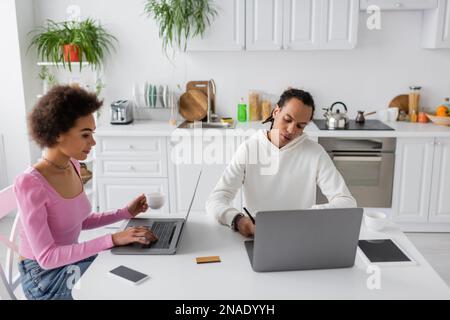 African american freelancers using laptops in kitchen Stock Photo