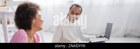 Positive african american couple using laptop at home, banner Stock Photo