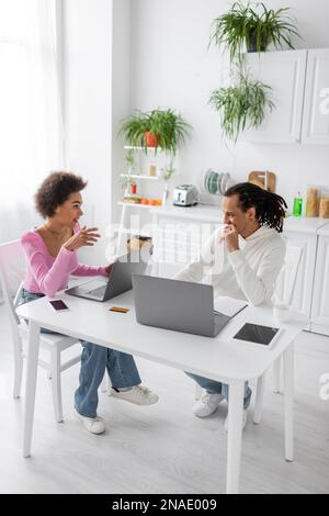 African american freelancers talking near devices in kitchen Stock Photo