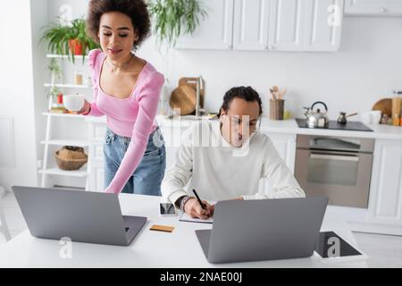African american freelancers using laptops while working in kitchen Stock Photo