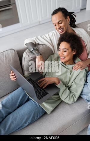 High angle view of excited african american couple using laptop on couch Stock Photo