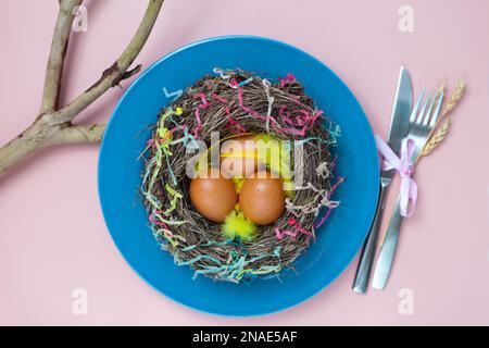 nest with eggs on blue plate on pink. Happy Easter. Stylish flat lay. Natural eggs spring Stock Photo