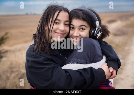 portrait of biracial sisters embracing and smiling Stock Photo