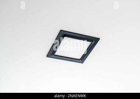 Black plastic rectangular LED lamp isolated on a white ceiling. Stock Photo