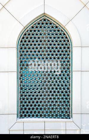 The window of a Muslim mosque behind bars in the form of a geometric hexagonal Islamic ornament. Abstract mosaic background. Stock Photo