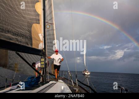 Sailing off the island of Grenada in the Caribbean with a rainbow in the storm clouds in the background. Scene from the 2011 Mt. Gay Rum yacht race... Stock Photo
