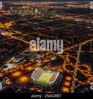 Aerial evening view of downtown Calgary, Alberta Canada and activity on the field at McMahon Stadium. Stock Photo