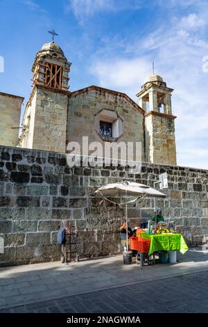 A vendor selling fresh orange juice on the street in Oaxaca, Mexico.  Behind is the Chapel of the Third Order of the Church of San Francisco. Stock Photo