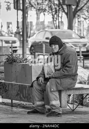 Bucharest, Romania - 12.29.2022:Homeless senior man holding a religious christian icon in the center of Bucharest. Stock Photo