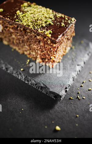 Chocolate cake with walnuts and pistachio isolated on black background. Pastry from homemade bakery Stock Photo