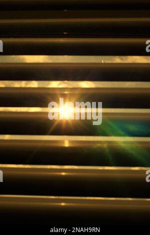 Closed blinds in a dark room, the sun shines through the blinds Stock Photo