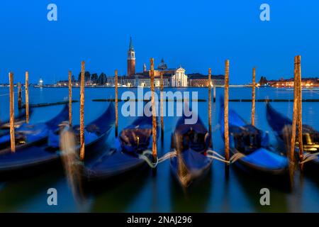 Venetian gondolas near St. Mark's Square in the evening light, blue hour, in the background the monastery of San Giorgio Maggiore, district of San Stock Photo