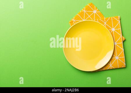 Top view on colored background empty round yellow plate on tablecloth for food. Empty dish on napkin with space for your design. Stock Photo
