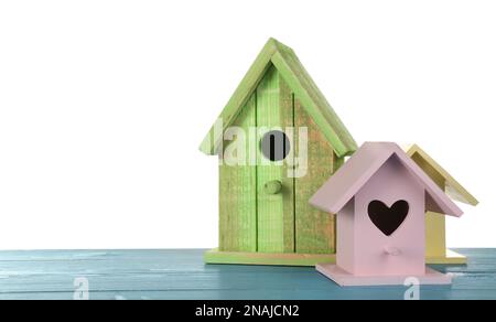 Three different bird houses on light blue wooden table against white background Stock Photo