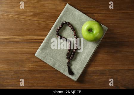 Rosary beads and apple on wooden table, top view. Lent season Stock Photo