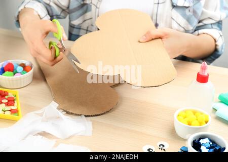 Woman making cardboard cloud at wooden table, closeup. Pinata diy Stock Photo
