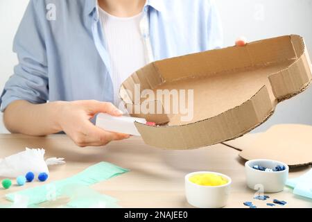 Woman making cardboard cloud at wooden table, closeup. Pinata diy Stock Photo