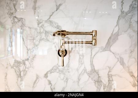 Gold Finish Pot Filler Faucet on Marble Tile Backsplash in Contemporary Kitchen Stock Photo