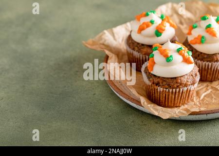 Carrot cupcakes with cream cheese frosting decorated with tiny frosting carrots, Easter dessert idea Stock Photo
