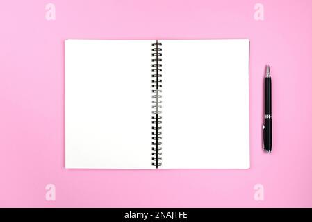 blank pages of open spiral notepad and pencil on pink background Stock Photo