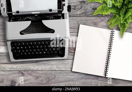 blogging or writing concept, directly above view of old typewriter and blank open note pad on wooden desk Stock Photo