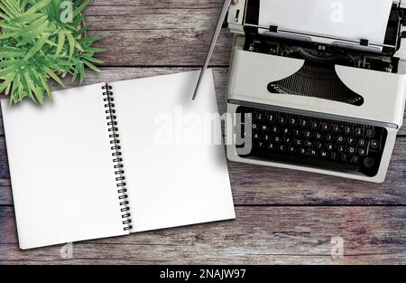 directly above view of old typewriter and spiral notepad on rustic wooden desk, blogging and journalism concept Stock Photo