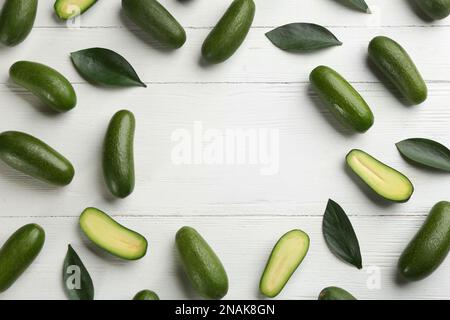 Frame made of fresh seedless avocados with green leaves on white wooden table, flat lay. Space for text Stock Photo