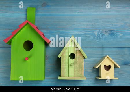 Three different bird houses on light blue wooden background Stock Photo