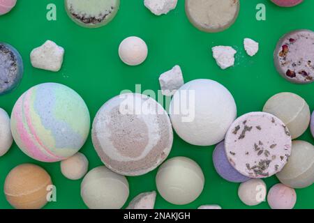 Multicolored bath bombs on a green background, top view. Stock Photo