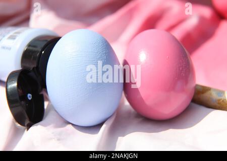 Easter crafts, painting a real egg with blue and pink paint for Easter with paintbrush, crafting, UK Stock Photo
