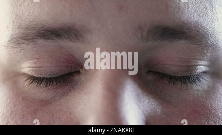 Person closing eyes in meditation and opening looking at camera. Macro close up of calm man eye in contemplation Stock Photo