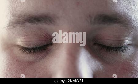 Person closing eyes in meditation and opening looking at camera. Macro close up of calm man eye in contemplation Stock Photo