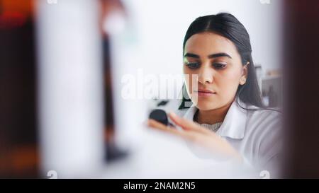 Young scientist removing a chemical bottle from a cabinet while working in a laboratory alone. One serious female medical biologist doing research on Stock Photo