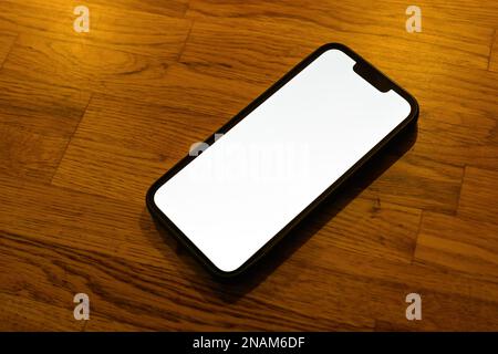 Mobile phone blank white screen mockup. Smartphone on hardwood parquet flooring. Selective focus. Stock Photo