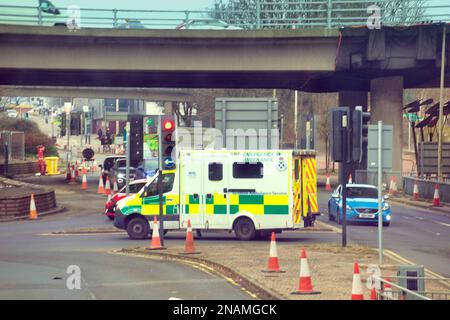 Emergency ambulance in traffic on a call crossing city road at traffic lights  under the m8 Stock Photo