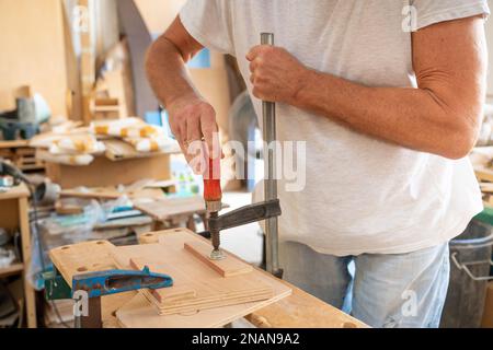 Closeup portrait of unknown unrecognizable man carpenter working in his joinery wooden furniture. Stock Photo