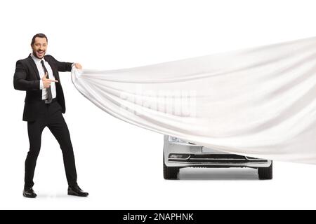 Car sales manager presenting a car behind a cloth and pointing isolated on white background Stock Photo