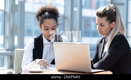 Two business women in modern office building cafe working with laptop Stock Photo
