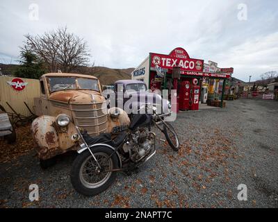 Burkes Pass Village, Canterbury, South Island, New Zealand - 2023: Old motorbike and rusty classic cars infront of Texaco historic antique gas station Stock Photo