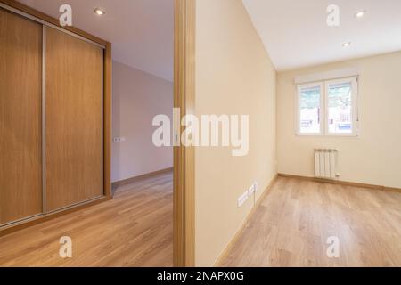 Empty rooms with laminate parquet flooring, built-in wardrobe with sliding doors and white aluminum windows Stock Photo