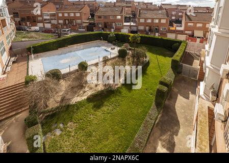 Aerial views of common areas of a building with a pool covered with canvas and gardens with grass and hedges Stock Photo