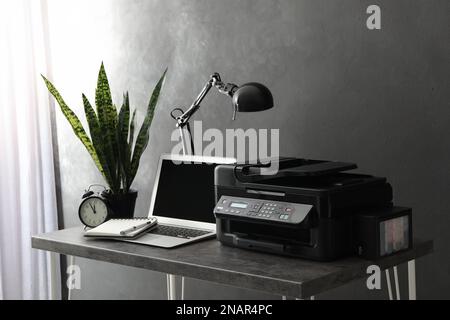 New modern printer and laptop on grey table in office Stock Photo