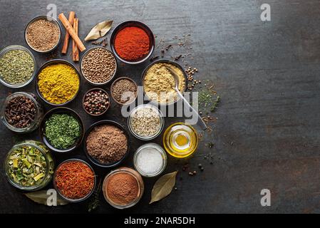 Colorful herbs and spices for cooking. Indian spices. On grey stone background. Top view. Stock Photo