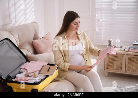 Pregnant woman packing suitcase for maternity hospital at home Stock Photo
