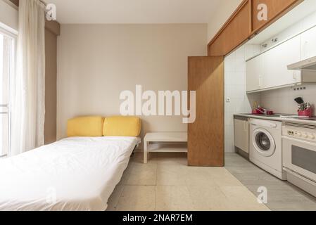 Studio apartment with kitchen behind oak doors and polished marble floors and extended sofa bed next to a balcony Stock Photo