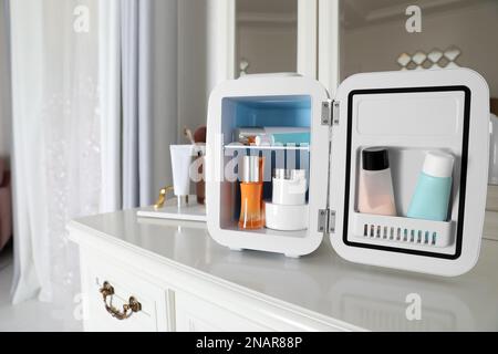 Mini Fridge with Cosmetic Products on White Vanity Table Stock